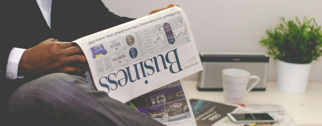 Professional reading a business newspaper at a desk, representing market insights and guidance from a business law attorney Long Island for corporate decision-making