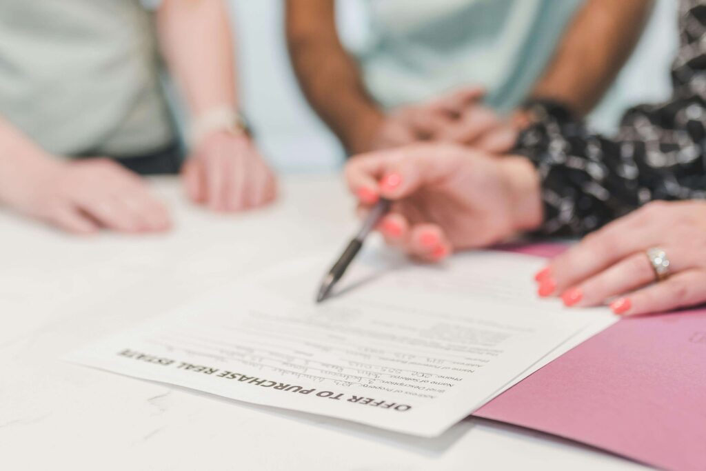 Close-up of a person signing an offer to purchase document with a pen, representing contract review and transaction support from a business law attorney Long Island
